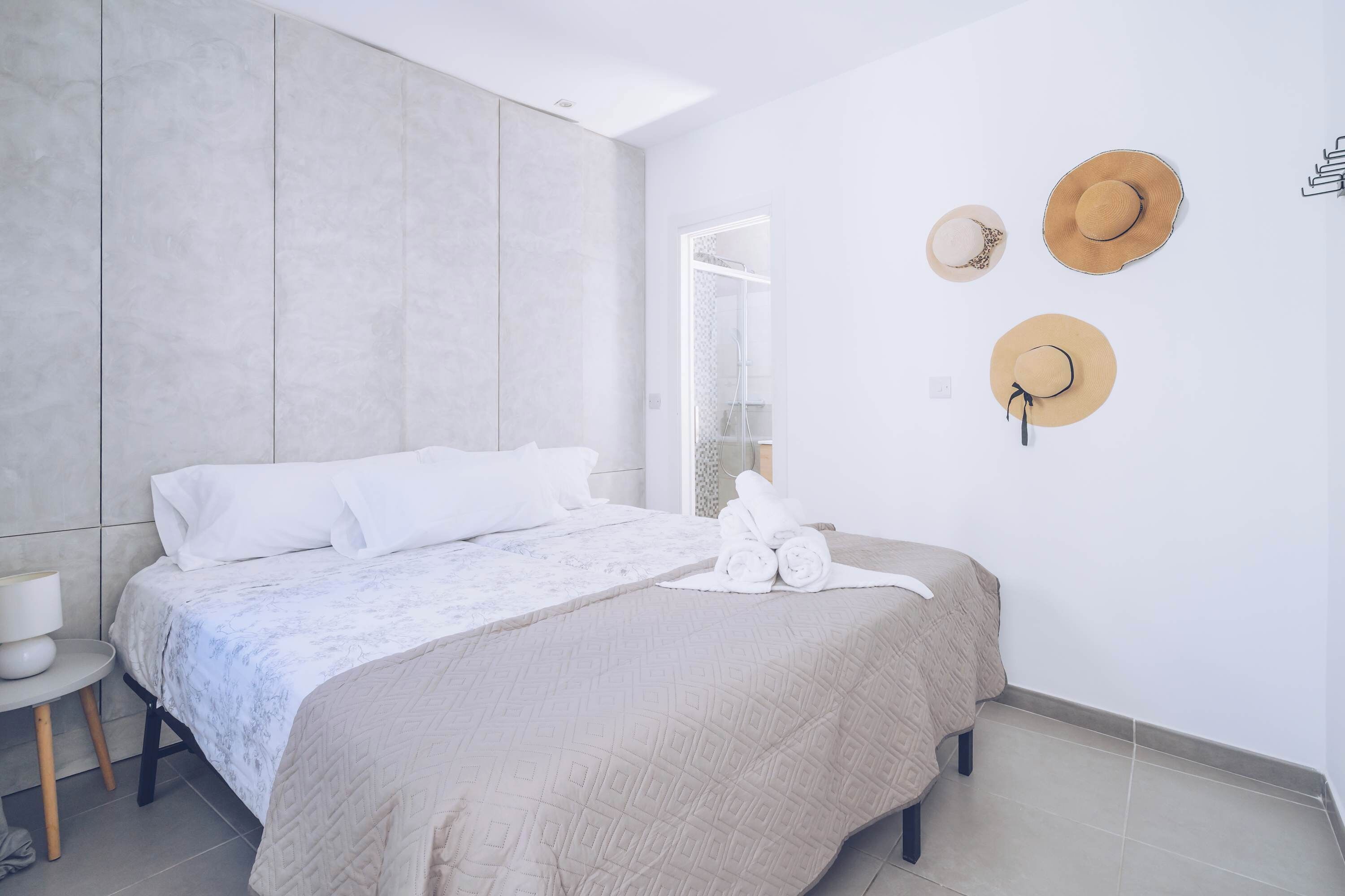 Une chambre à coucher moderne, avec un lit, une table de chevet et un porte-chapeaux fixé au mur.