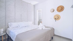 A modern bedroom with a bed, a nightstand, and a wall-mounted hat rack.