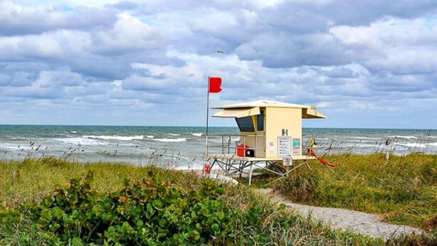 A lifeguard tower with a red flag, a beach path, and the ocean. - Beach Cottage: Cozy I Clean I Family I Beaches (Port St. Lucie)
