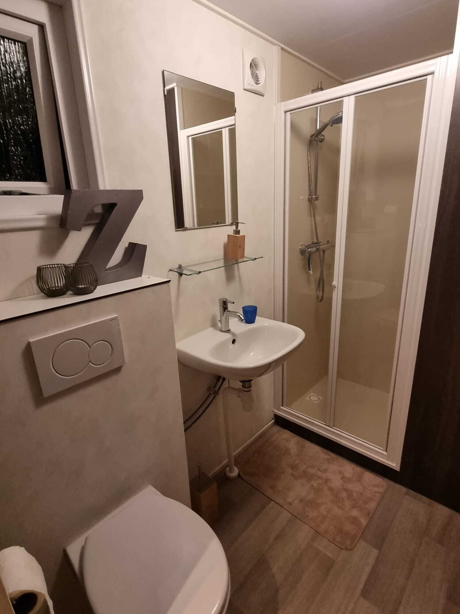 Ein Badezimmer mit Toilette, Waschbecken, Spiegel, Dusche und einer großen Dekoration mit der Zahl 7.