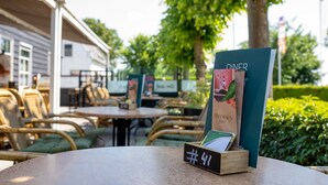 Terras met tafels en stoelen, een bord en een houten bord met een nummer.