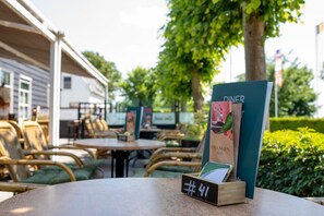 Terrasse mit Tischen und Stühlen, einem Schild und einem Holzschild mit einer Nummer.