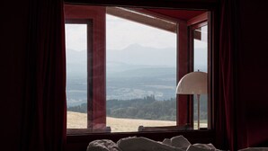 A bedroom with a bed, a window with curtains, and a view of a landscape. - Architect's house (Vollore-Montagne)