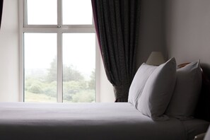 Una habitación de hotel con cama, lámpara y ventana con cortinas.