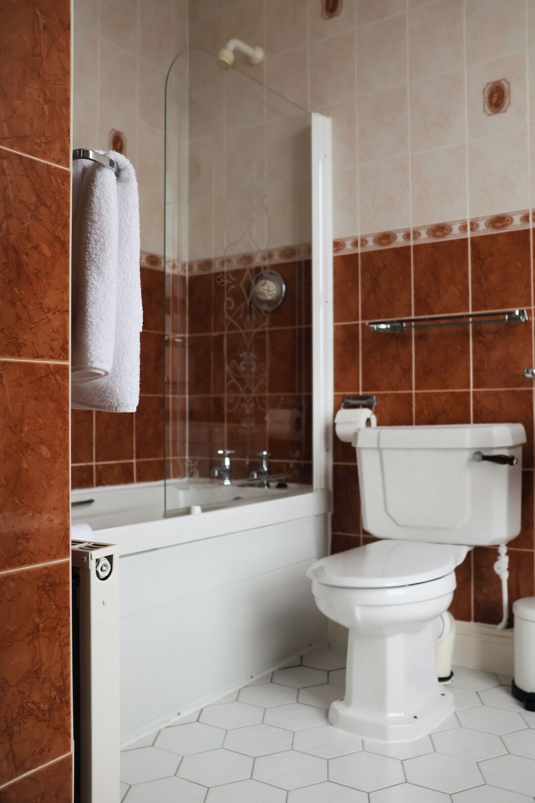 Ein Badezimmer mit Toilette, einer Duschkabine und einem Handtuch auf einem Haken.