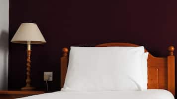 A bed with white bedding, a wooden headboard, a bedside lamp, and a framed picture on the wall.