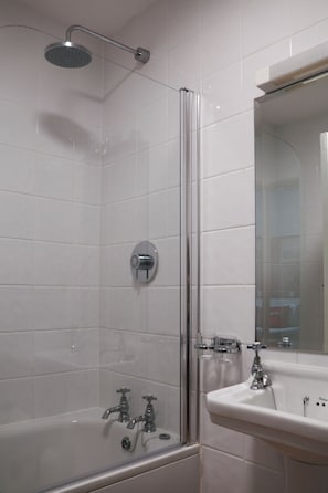Un baño moderno con ducha de vidrio, lavamanos blanco y espejo.