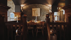 A dining area with stone walls, wooden furniture, and a fireplace.