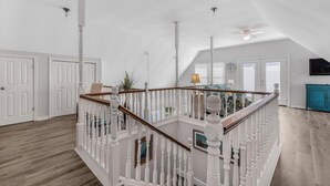 A spacious loft with a high ceiling, white walls, and a wooden staircase. - 🌞🐠Waterfront | Walk to the Beach | Community Boat Launch | Happy Daze (Gulf Shores)
