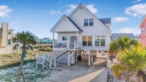 A two-story beach house with a balcony, a covered porch, and a staircase leading to the entrance. - 🌞🐠Waterfront | Walk to the Beach | Community Boat Launch | Happy Daze (Gulf Shores)