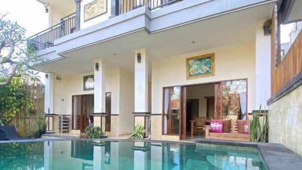 A two-story house with a swimming pool, a balcony with a railing, and a door leading to an interior space. - Danu House Ubud (Ubud)