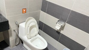 Uma casa de banho moderna com sanita, secador de mãos e um contentor de lixo.