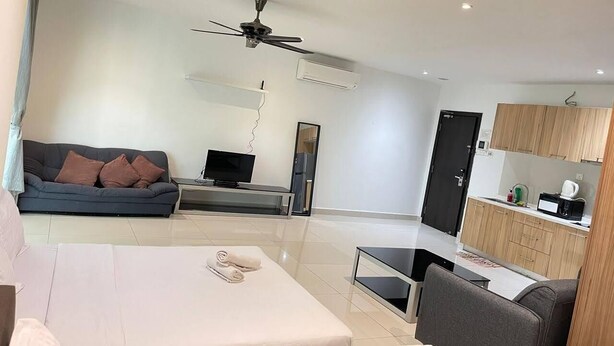 Uma sala de estar moderna com sofá, televisão, ventoinha no teto, mesa de jantar e cozinha com armários e eletrodomésticos.