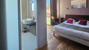 Un dormitorio moderno con una cama grande, un baño con lavamanos y vistas al exterior.