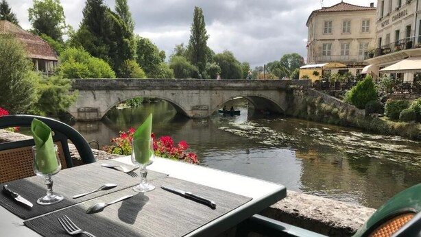 Una mesa con vistas a un río, un puente y un edificio que dice 'HOTEL CHABRUL'.