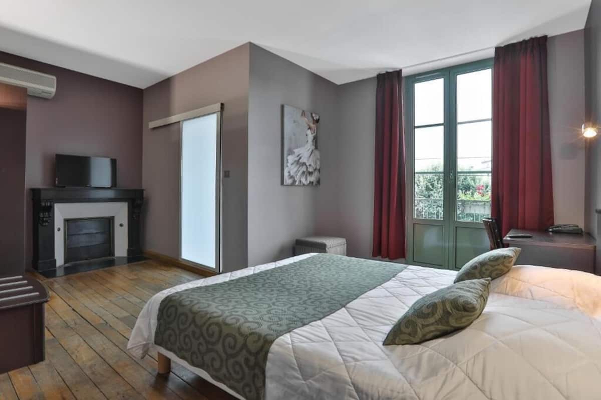 Un dormitorio con cama, televisión, chimenea y ventana con cortinas.