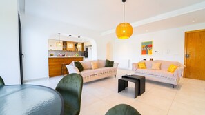 A modern living room with a sofa, a coffee table, and a dining area with a table and chairs. - Residence Jannet 1 Luxury Seaside 3 bedrooms (Mrezga)