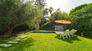 A backyard with a swimming pool, stone wall, and outdoor seating area. - Residence Jannet 1 Luxury Seaside 3 bedrooms (Mrezga)