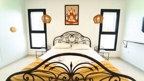 Ein Schlafzimmer mit einem Bett, zwei Nachttischen, zwei Wandleuchten, einem gerahmten Kunstwerk und einem Fenster.