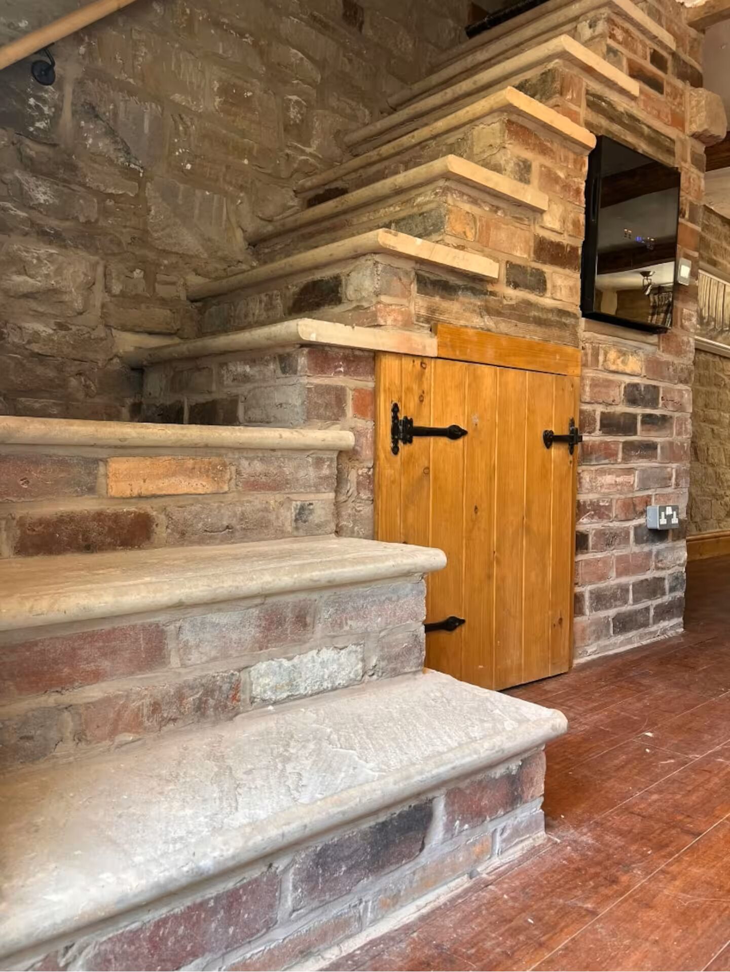 A stone staircase leading to a wooden door with a mirror above it.