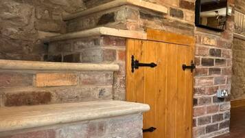 A stone staircase leading to a wooden door with a mirror above it.