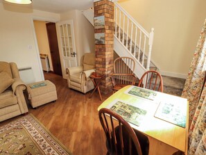 A dining area with a wooden table, chairs, and a brick accent wall. - Burn Bank (Appleby-in-Westmorland)