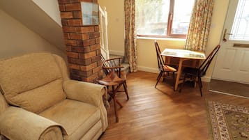 A living room with a brick fireplace, a sofa, a dining table with chairs, and a window with curtains.