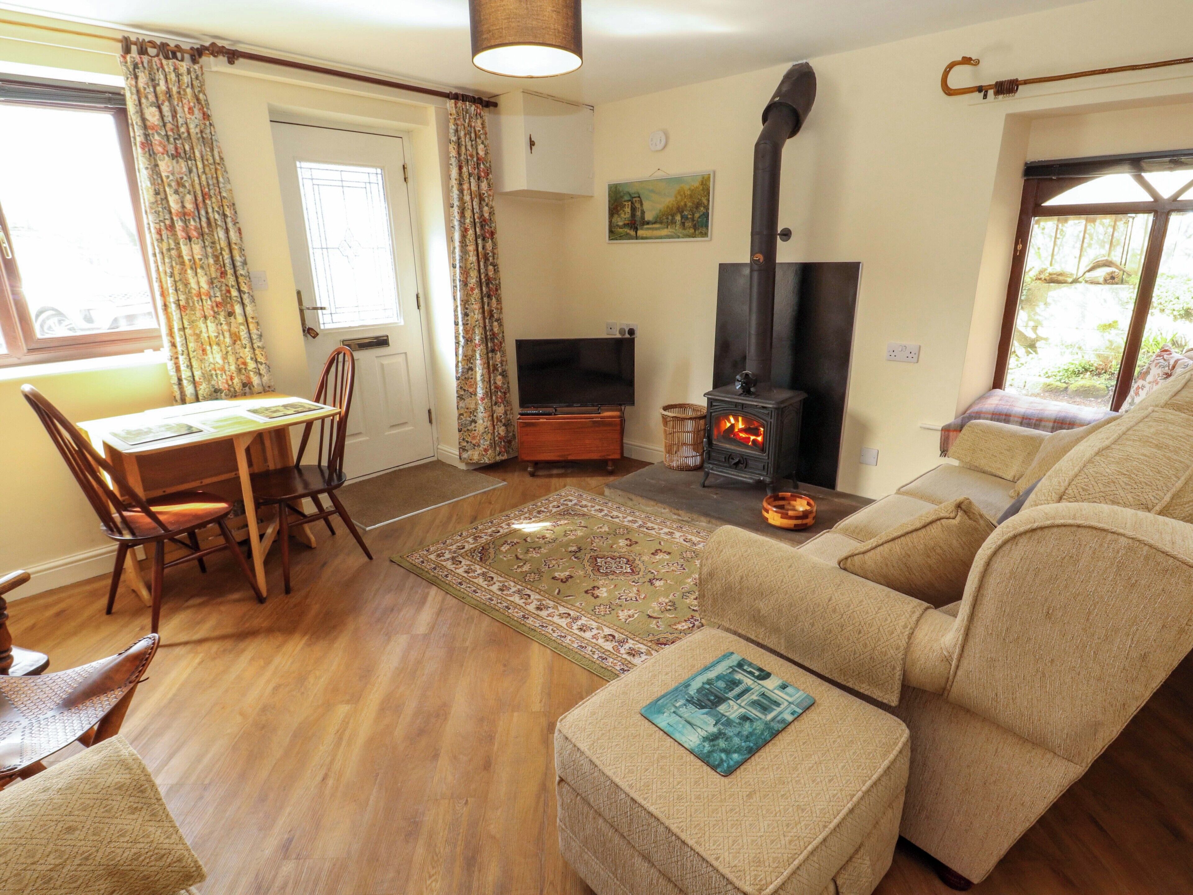 A living room with a sofa, a table with chairs, a television, a fireplace, and a window with curtains.