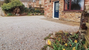 A stone building with a gravel driveway and a blue door. - Burn Bank (Appleby-in-Westmorland)