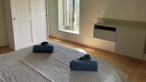 Ein Schlafzimmer mit Bett, Fenster, Kleiderschrank und Schreibtisch.