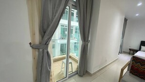 Ein Zimmer mit einer Schiebeglasdoor zu einem Balkon, einem Bett und einem kleinen Tisch.