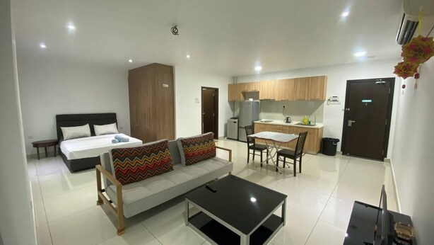 Ein modernes Hotelzimmer mit Bett, Sofa, Esstisch und Küchenzeile.