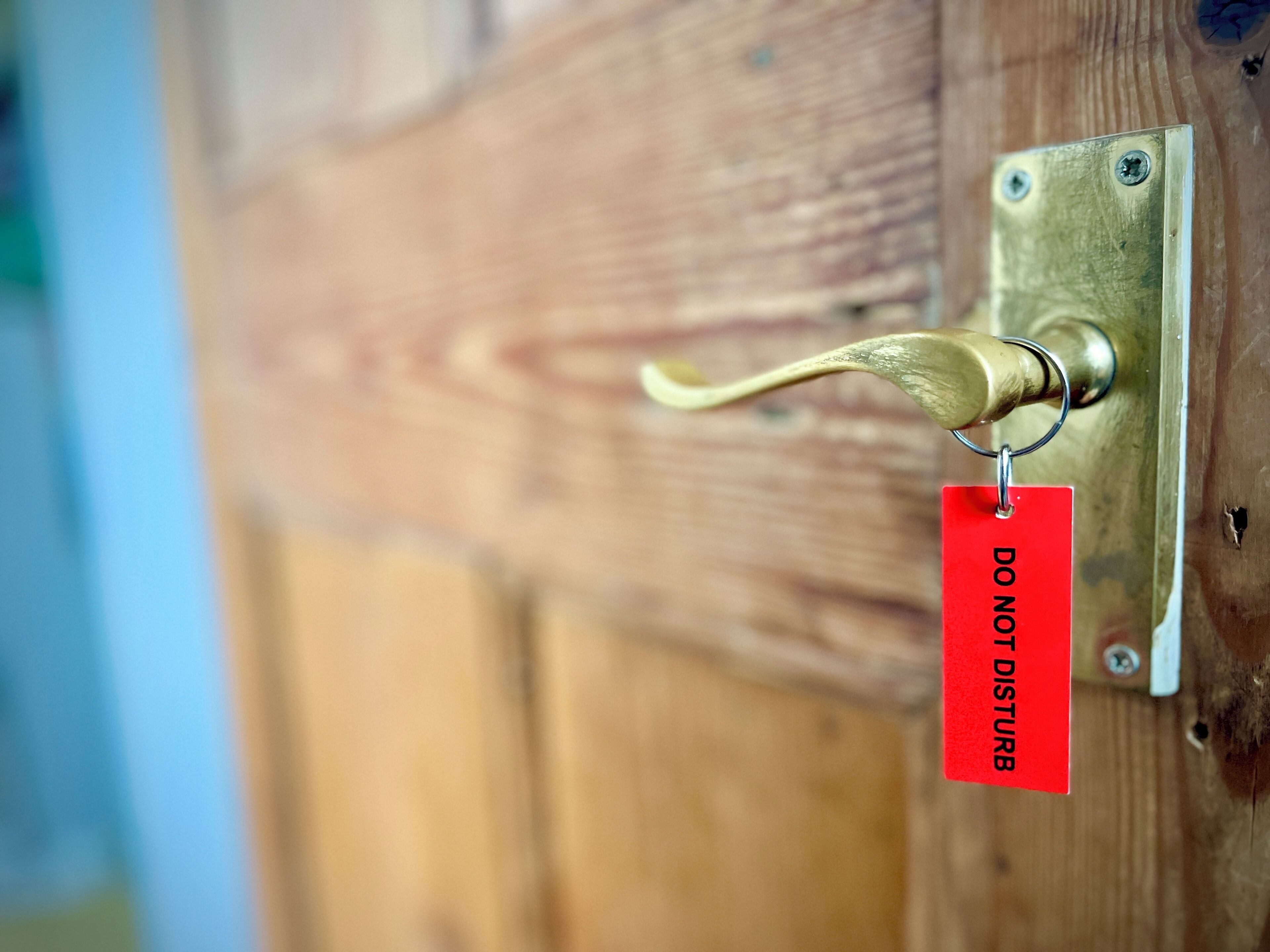 A brass door handle attached to a wooden door with a 'DO NOT DISTURB' sign.