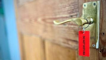 A brass door handle attached to a wooden door with a 'DO NOT DISTURB' sign.