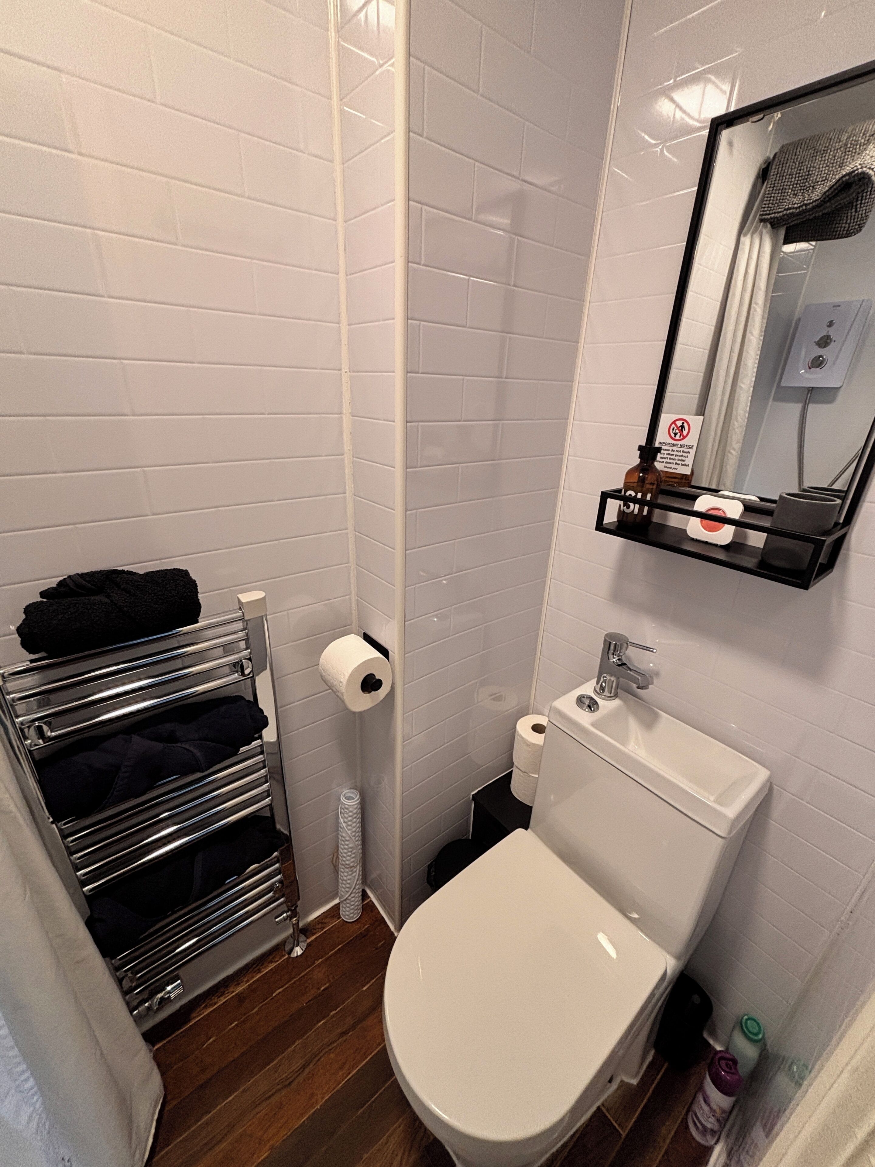 A bathroom with a white toilet, a sink, a towel rack, and a mirror.