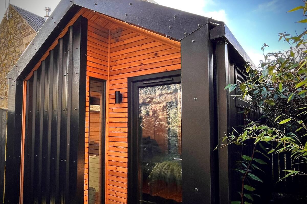 A modern building with a wooden exterior, a glass door, and a metal roof.