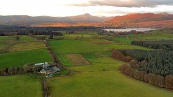 A rural landscape with fields, a small building, and distant mountains.