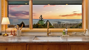 A kitchen with a large window, a sink, and various kitchen items.