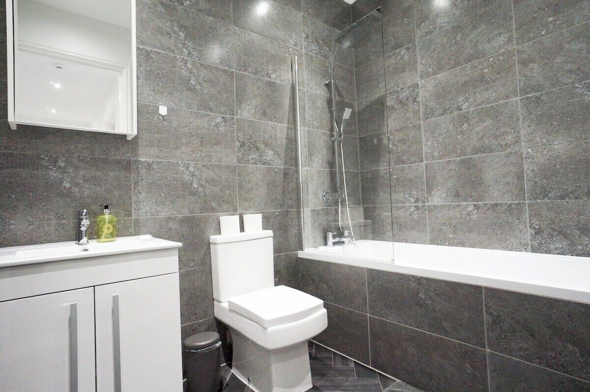 A bathroom with a white toilet, a white sink, a bathtub, and a shower area.