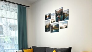 Un salon moderne avec un canapé gris, des coussins jaunes, une petite table d’appoint verte et une lampe jaune.