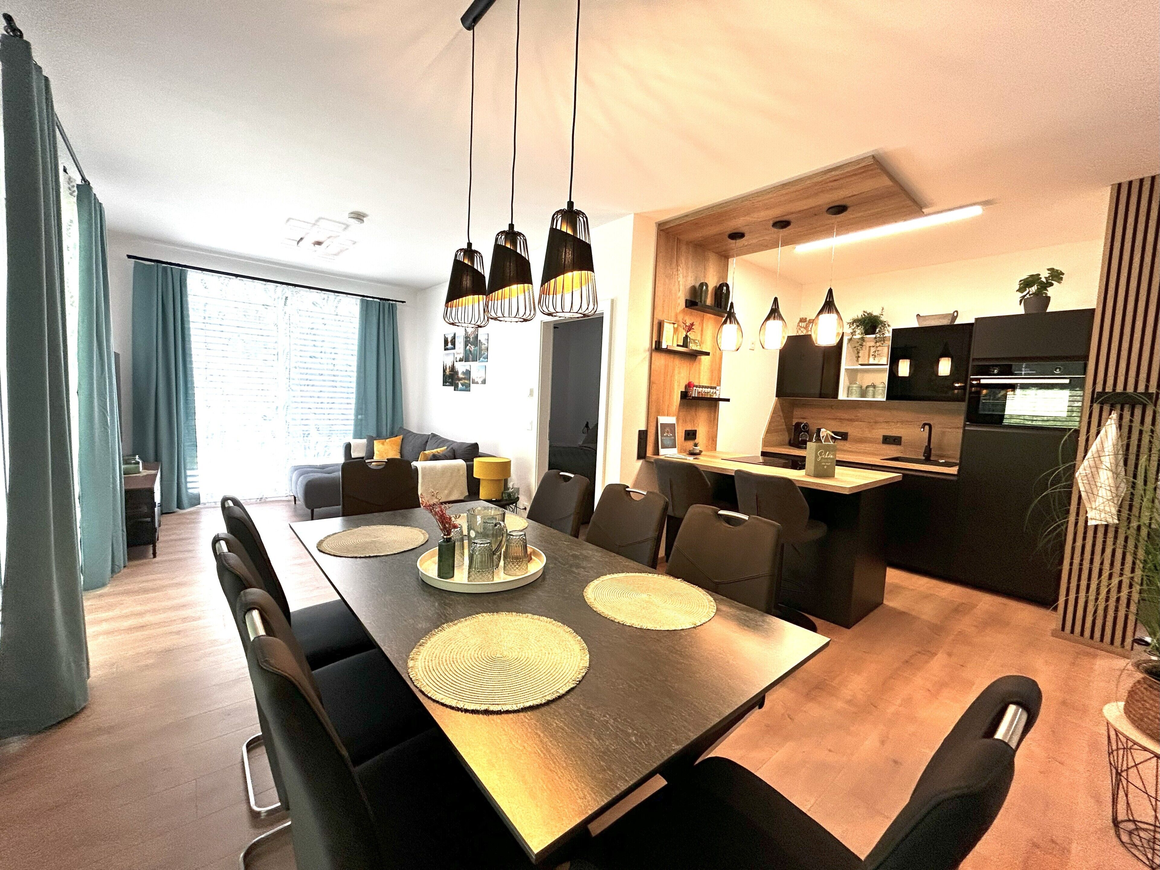 Un comedor moderno con una mesa larga, sillas e iluminación colgante.