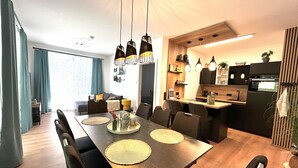 Un espace de salle à manger moderne avec une longue table, des chaises et des luminaires suspendus.