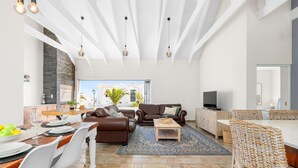 A spacious living area with a dining table, sofas, a TV, and a kitchen in the background. - Shelley Point 36 on 20th Street (St. Helena Bay)