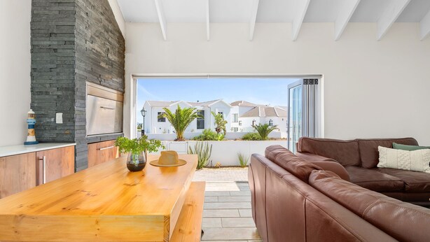A modern kitchen with a stone wall, wooden table, and a brown leather sofa. - Shelley Point 36 on 20th Street (St. Helena Bay)