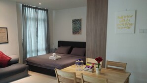 Ein Hotelzimmer mit einem Bett, einem Holzespeisetisch mit Stühlen, einem kleinen Tisch mit Blumenvase und einer Wand mit einem motivierenden Zitat.