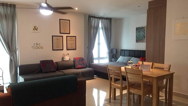 Ein Wohnzimmer mit einer Couch, einem Esstisch mit Stühlen, einem Bett, einem Deckenventilator und gerahmten Zertifikaten an der Wand.