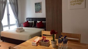 Ein Hotelzimmer mit zwei Betten, einem Esstisch mit Frühstücksgebäck und -speisen, einer Vase mit Blumen und einem motivierenden Zitat an der Wand.