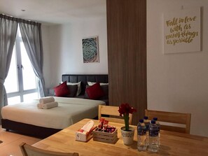 A hotel room with two beds, a dining table with breakfast items, a vase with flowers, and a motivational quote on the wall. - KSL Studio Room #19 (Johor Bahru)