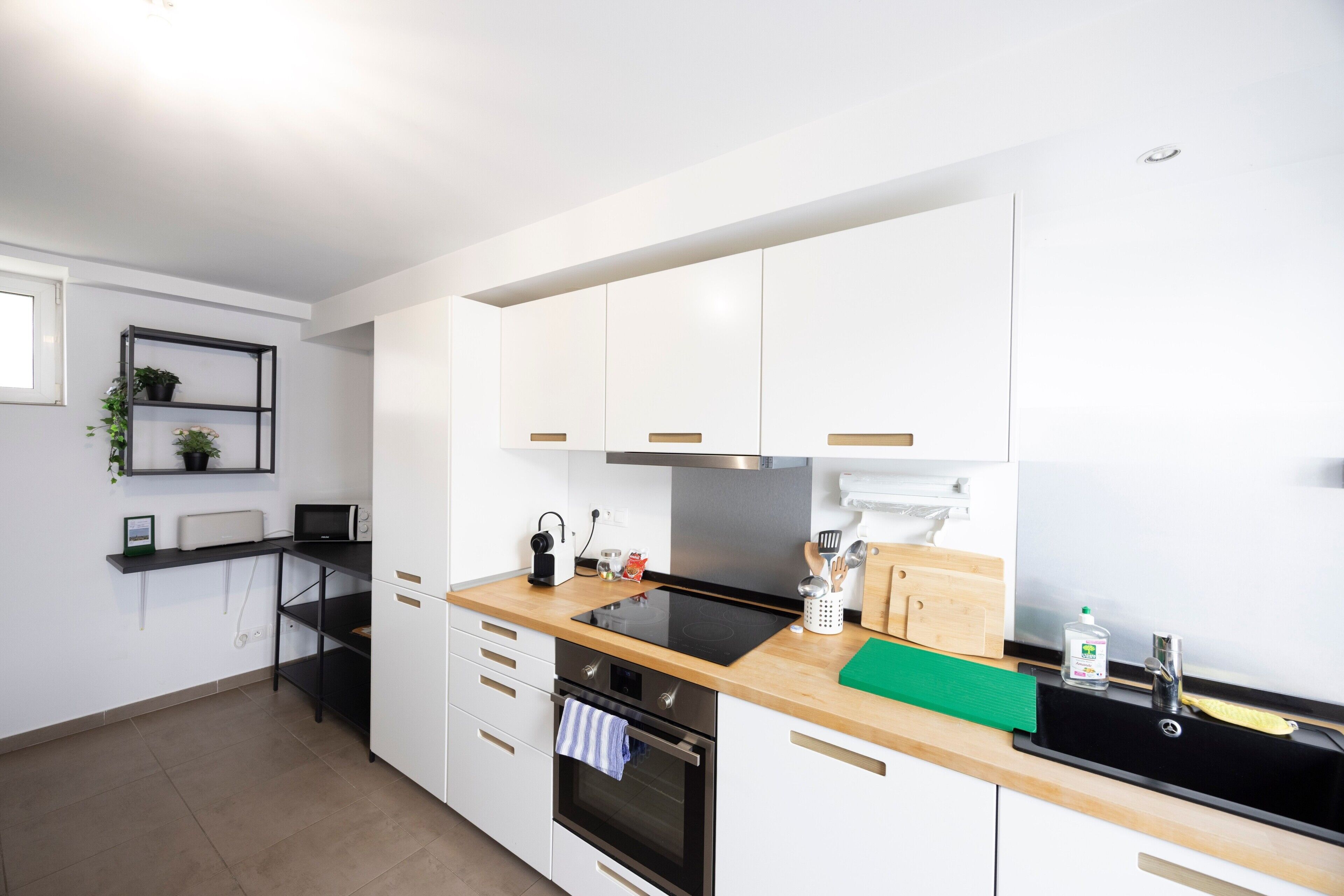 Een moderne keuken met witte kasten, een zwart aanrecht, een fornuis en een spoelbak.