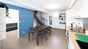 A modern kitchen with a dining area, a staircase, and a living room with a sofa.